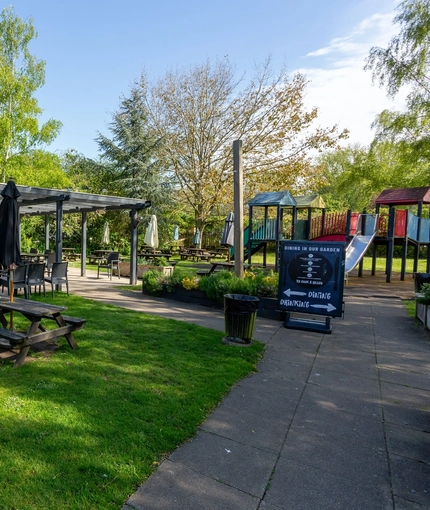 Exterior beer garden of a pub with a play area and a seating area.