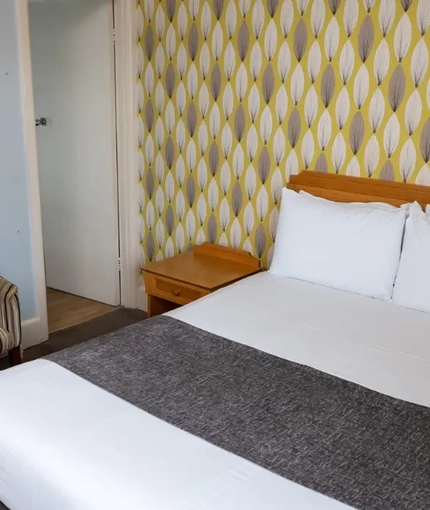 A interior double hotel bedroom with wardrobe, bedside tables and lamp at The Commodore.