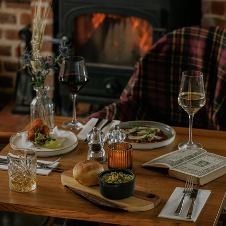 An advertising image of 3 starter dishes from the Burns Night menu sat on a table within the interior restaurant seating area at The Crown.