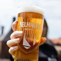 An exterior image of a person holding a pint of Belhaven Belter.