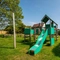 The exterior beer garden seating area and children's play area at The Walkford, with wooden picnic tables, and climbing frame with a slide.