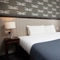 A bed, bedside table and window in one of the hotel rooms in The Charnwood Arms.