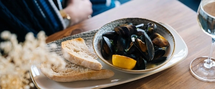 A bowl of mussels on a wooden table.