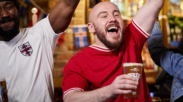 A mixed group of people holding a drink and cheering.