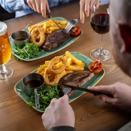 People sitting eating steak and chips.