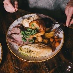 A close up lifestyle image of a Mother's Day Roast main dish sat on a table within the interior restaurant seating area at a Heritage venue.