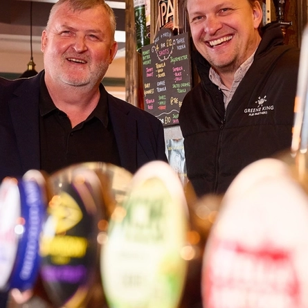 A Pub Partners image showing 2 people stood behind the bar at the Hertford Bell.