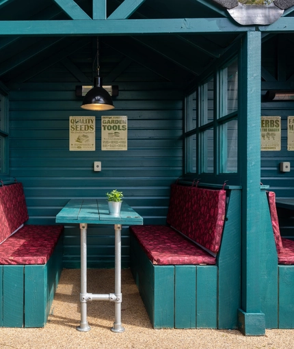 One of the under cover beer garden seating areas at the Golden Hind, made up of three booth seating areas with padded seats.