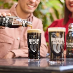 An image of 2 people enjoying Belhaven Black within the exterior beer garden seating area.