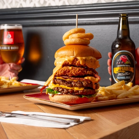 A close up image of a burger and various drinks sat on a table within the interior restaurant and seating area at a Hungry Horse venue.