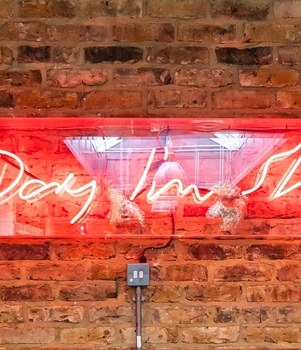 The interior decor featuring a neon sign on an exposed brickwork feature wall in the Shuffle Board area at The Vine.