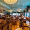 The bar and interior restaurant seating area of the Blue Posts in St James's, with upholstered booth seats, TVs on the walls, and glasses hanging in racks above the bar.