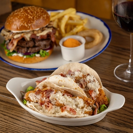A roasting dish containing Chicken Caesar Tacos on an indoor wooden table.