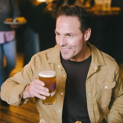 An image of a person enjoy a Fish & Chips dish with a pint of Hazy Day sat within the interior restaurant seating area at an Urban Core Venue.