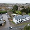An aerial view of the exterior facade and car park of the Tredegar Arms in Bassaleg, with a view of the surrounding area and the church next to the pub.