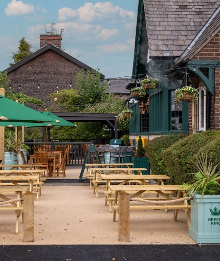 The exterior patio beer garden seating area with wooden benches, planters and hanging baskets at The Church View Inn.