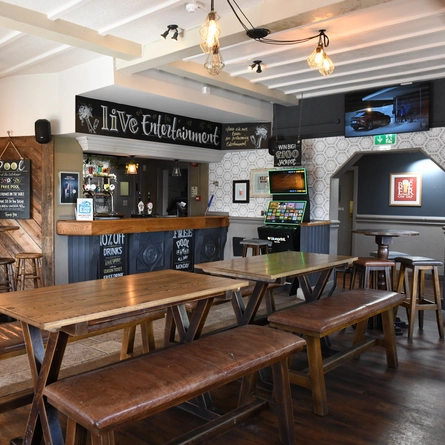 Interior bar area and dining area of a pub with a gambling machine and a TV.