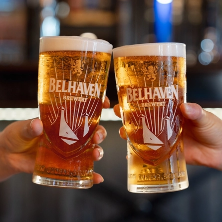 An image of 2 people holding a pint of Belhaven Belter each engaging in a cheers.