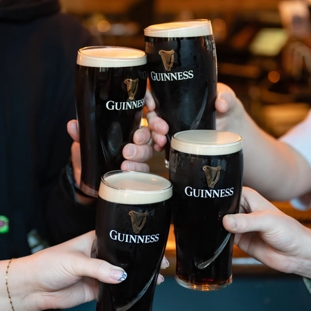 People doing cheers with pints of Guinness