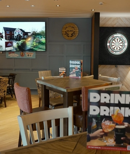 The interior restaurant seating area of The Steam Turbine, with a TV on the wall, and a dartboard.
