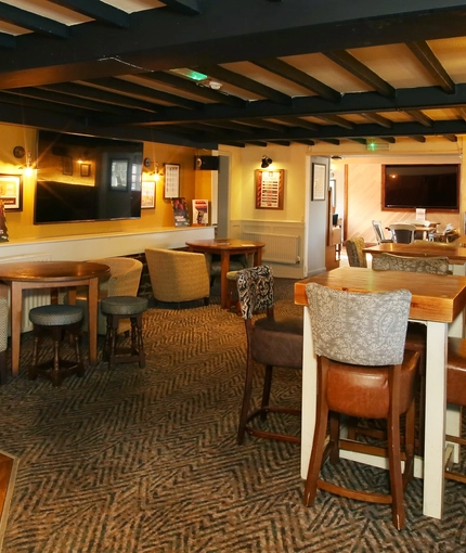 Interior dining area of a pub with a few TVs and a fireplace.