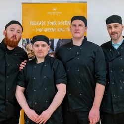 A group opf Kitchen staff stood looking at the camera.