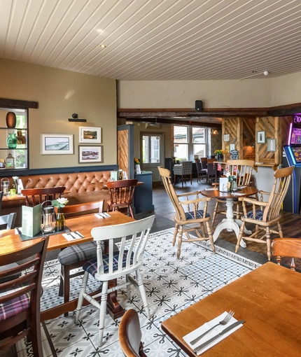 Interior dining area of a pub with a bar, a few gambling machines and a TV.