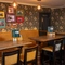 An interior restaurant seating area at The Royal Oak; with an upholstered booth seat along one side of the room, and framed artwork on the floral wallpapered wall above it.