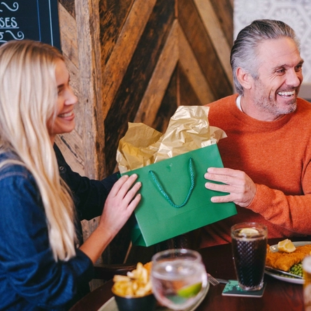 A family out for a meal for Fathers day seated in the interior restaurant of a Greene King pub.