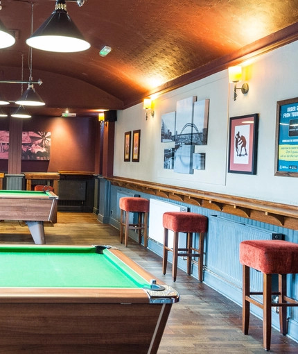 Interior seating area of a pub with two pool tables.