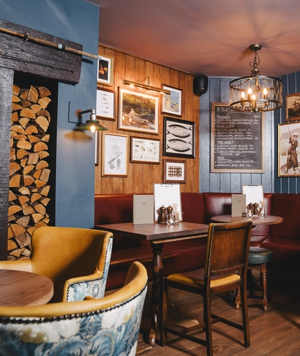 An interior restaurant seating area at Ye Olde Swan, with an upholstered corner seat, and framed artwork on the walls.