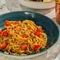 An advertising image showing a bowled Crab Mafalde Pasta dish sat on a table within the exterior beer garden seating area at a Crafted venue.