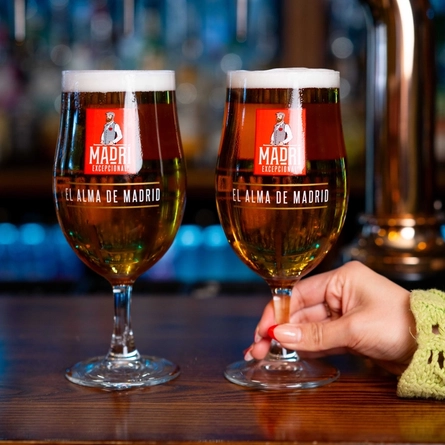 The hands of two people holding a pint of Madri each on a bar.