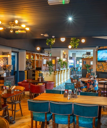The interior restaurant seating area of the Malvern Tavern in Shirley, with a large brick fireplace, and a TV on the wall.