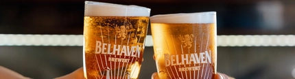 An image of 2 people holding a pint of Belhaven Belter each engaging in a cheers.