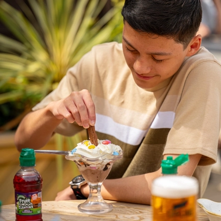 A family seated at an outdoor table in a beer garden, enjoying a dessert..