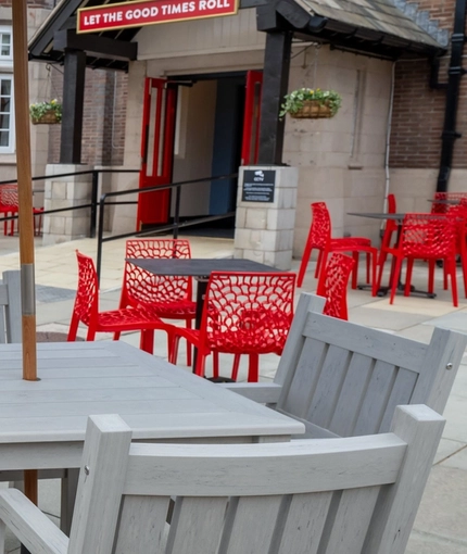 The exterior beer garden seating area at The Railway in Meols, with wooden tables and chairs, and shade umbrellas.