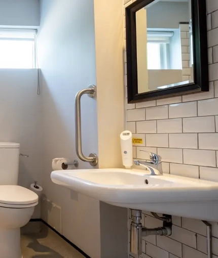 The interior accessible hotel bathroom with toilet, sink and shower with shower chair at the Cedars Inn.