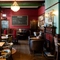 The interior restaurant seating area at the King's Head in Bayswater, with dark wood floors, upholstered chairs, and a fireplace.