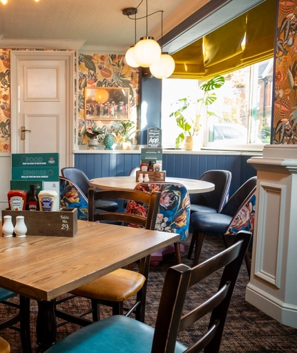 The interior restaurant seating area at The Grosvenor in Felixstowe, with a fireplace, and a TV on the wall above it.