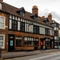A view from across the road of the exterior facade and signage of The Talbot in Worcester; with flower baskets hanging from the brick walls.