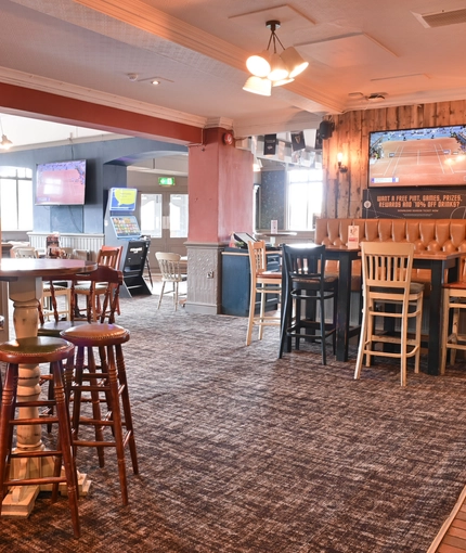 Interior dining area of a pub with TVs playing tennis and a gambling machine.