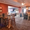 Interior dining area of a pub with TVs playing tennis and a gambling machine.