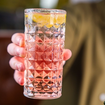 A hand holding a drink in a glass.
