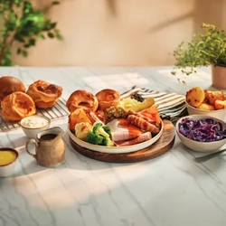 A plated carvery with a said of gravy, yorkshire puddings and roast potatoes in bowls for Farmhouse Inns