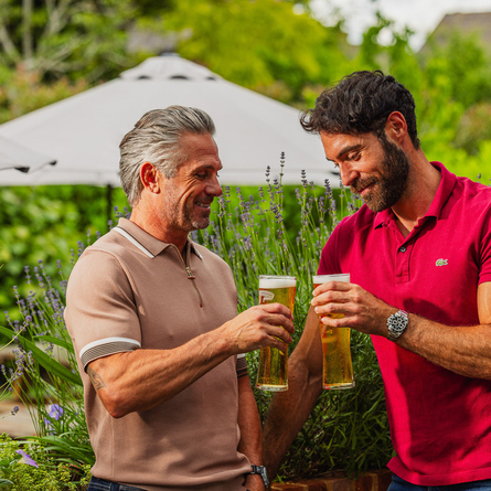 An image of two people enjoying pints of Peroni within the exterior beer garden seating area at a Crafted venue.
