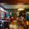 The upper floor interior restaurant seating area at The Globe in Marylebone; with parquet flooring, wood panelled walls, interactive darts, and a TV on the wall.