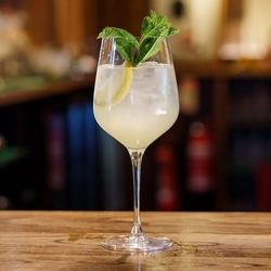 A cocktail in stemmed goblet glassware on a bar.