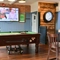 Interior seating area of a pub with a pool table, a dartboard and a TV.