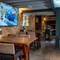 An interior restaurant seating area at The Royal Oak; with wooden flooring, wooden beams on the ceiling, and a large TV on a stone wall.